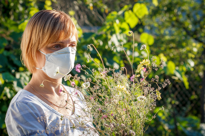 woman wearing mask near flowers